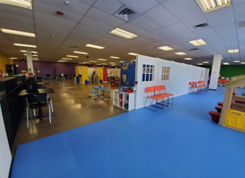 Brightly colored indoor play area with seating, play equipment, and open space for children.