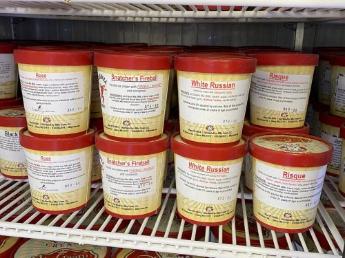 Ice cream tubs on a shelf, featuring flavors like Snatcher's Fireball, White Russian, and Risque, with detailed labels.