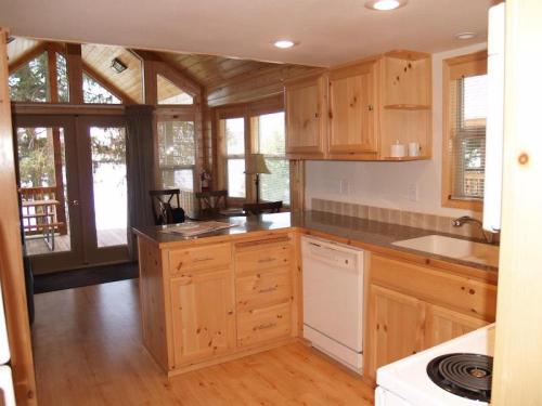 Cozy wooden kitchen with light-colored cabinets, a countertop, and large windows overlooking a deck.