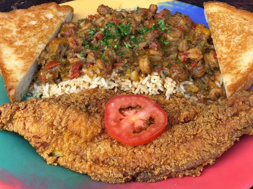 A colorful plate featuring fried fish, rice, a vegetable medley, and two slices of toasted bread with a tomato slice.