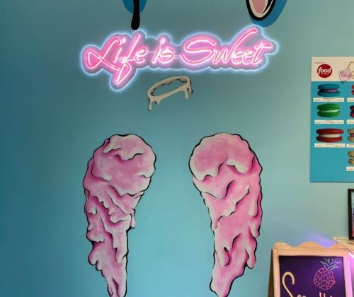 A colorful wall mural featuring the phrase "Life is Sweet" and two pink cotton candy illustrations.