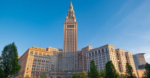 Views of Terminal Tower, a lookalike attraction in Ohio, featuring a prominent clock tower and surrounded by greenery.
