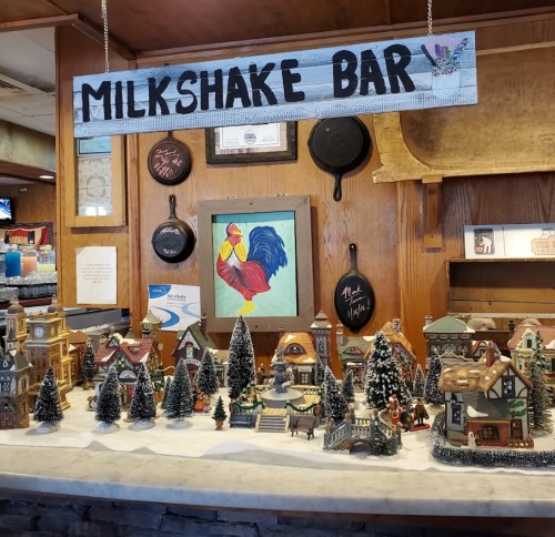 A cozy milkshake bar display featuring a festive village scene with miniature buildings and trees.