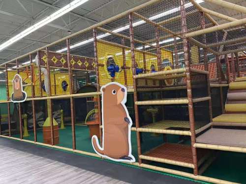 Indoor play area featuring a colorful jungle gym with animal-themed decorations and climbing structures.