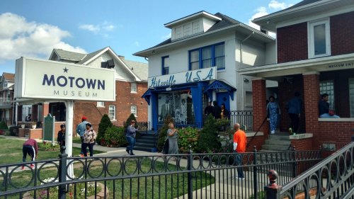 Exterior of the Motown Museum, with visitors and a sign, showcasing a historic building in a vibrant neighborhood.