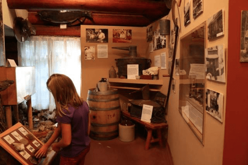 A child examines historical photos in a museum exhibit featuring artifacts and information on the walls.