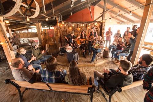 A lively gathering in a rustic venue with musicians playing instruments and an audience enjoying the performance.
