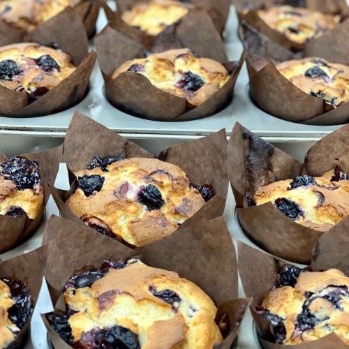 Freshly baked muffins with blueberries, nestled in brown paper liners, arranged in a baking tray.
