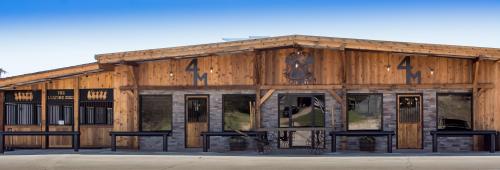 A rustic wooden building with stone accents, featuring large windows and a sign reading "4M" above the entrance.