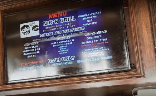 Menu display for Nic's Grill featuring burgers, sides, and daily specials. Cash only. Hours listed for weekdays and Saturday.