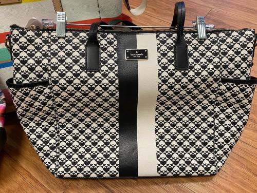 A large tote bag with a patterned design in black and cream, featuring a central stripe and leather accents.