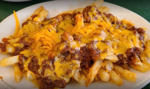 A plate of loaded fries topped with chili and melted cheddar cheese.