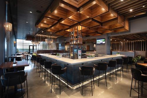 Modern restaurant interior featuring a stylish bar, wooden ceiling, and sleek seating arrangements.