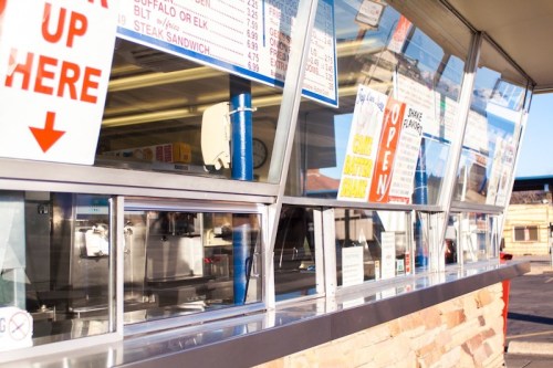 A food stand with a service window displaying menus and signs, featuring various food options and an "Open" sign.