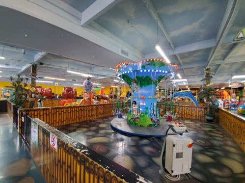 A colorful indoor amusement area featuring a carousel, games, and vibrant decorations.