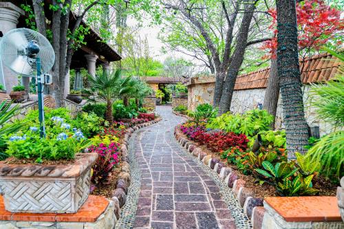 A winding stone pathway surrounded by vibrant flowers and lush greenery, leading through a serene garden.