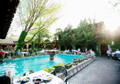 A serene outdoor dining area with a fountain, surrounded by lush greenery and people enjoying their meals.