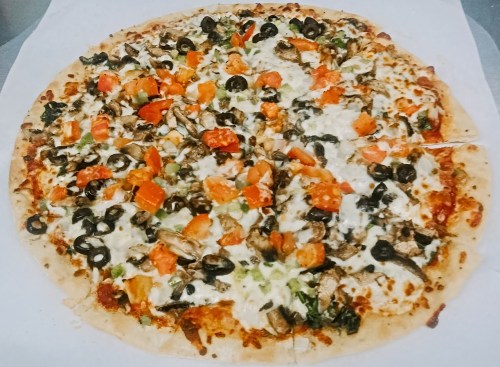 A large pizza topped with mushrooms, tomatoes, green peppers, and black olives on a golden crust.