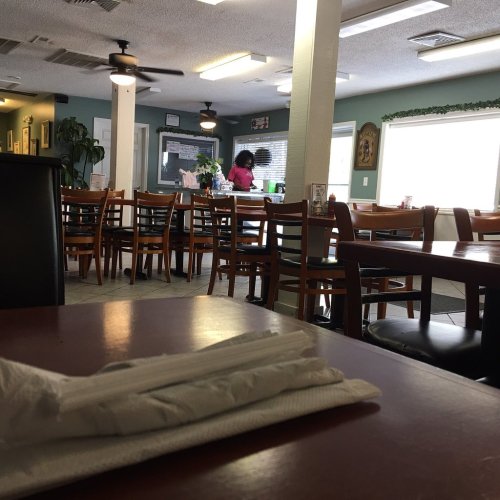 A cozy restaurant interior with empty tables and a person in the background attending to a task.