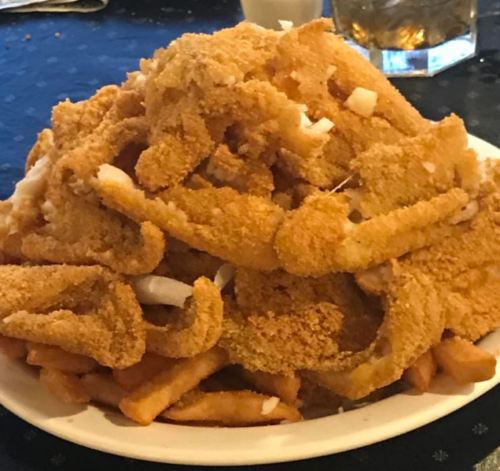 A large plate piled high with golden-brown fried food, including crispy strips and French fries.