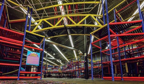 Colorful indoor play structure with multiple levels, nets, and slides, designed for children's activities and fun.