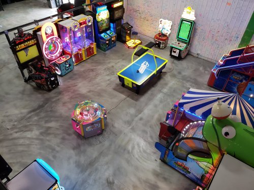 Aerial view of an arcade featuring various colorful games and machines on a concrete floor.