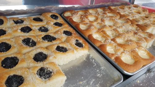 Two trays of freshly baked pastries: one with poppy seed filling and the other with a creamy filling, both sprinkled with sugar.