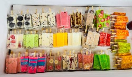 A colorful assortment of ice pops in various flavors, neatly arranged in a cooler.