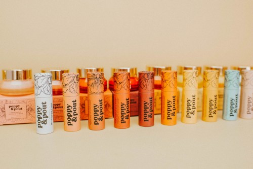 A collection of colorful lip balms and skincare products from Poppy & Pout arranged neatly against a light background.