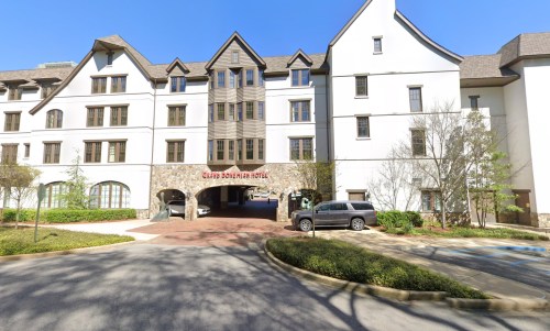 Exterior view of the Grand Dunes Hotel, featuring a multi-story building with a stone entrance and parked cars.