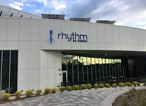 Modern building exterior with the sign "rhythm on Monroe" and landscaped pathway in front.