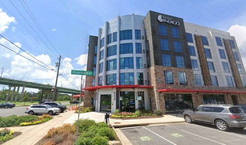 Exterior view of Hotel Indigo, featuring modern architecture and landscaping, with Riverfront Ct street sign in foreground.