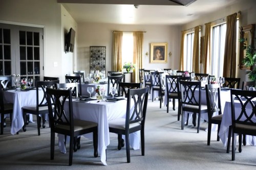Elegant dining room with tables set for a meal, featuring white tablecloths and decorative centerpieces.