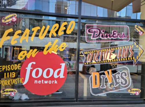 Window display featuring "Featured on the Food Network" with signs for "Diner," "Drive-Ins," and "Dives."