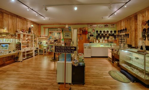 Interior of a museum gift shop featuring displays of souvenirs, artifacts, and a sign for the museum entrance.