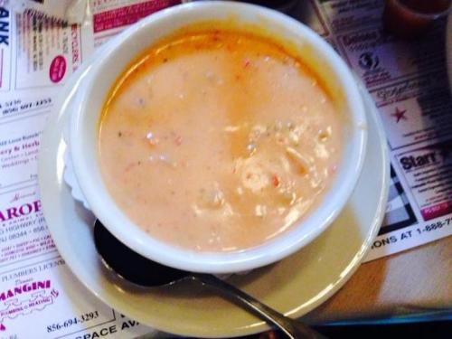 A bowl of creamy soup with a smooth texture, served on a plate with a spoon beside it.