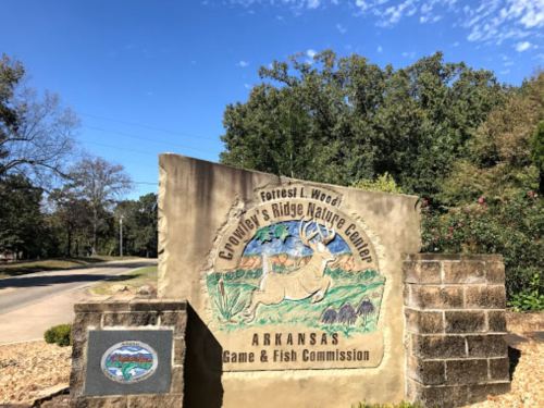 Sign for Crowley's Ridge Nature Center in Arkansas, featuring a deer and nature-themed artwork against a stone backdrop.