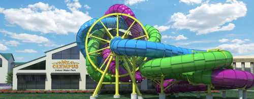 Colorful water slides twist and turn outside the Olympus Indoor Water Park under a bright blue sky.