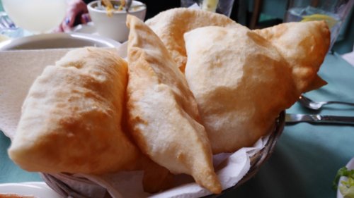 A basket of golden, crispy fried pastries resting on a table.