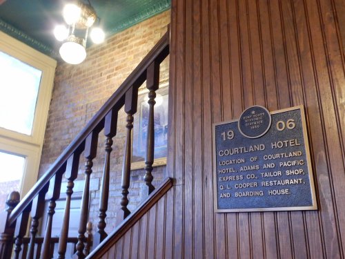 Interior view of the Courtland Hotel, featuring a wooden staircase and a historical plaque on the wall.