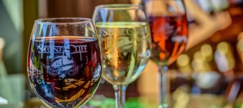 Three glasses of wine in varying colors—red, white, and rosé—set against a blurred background.