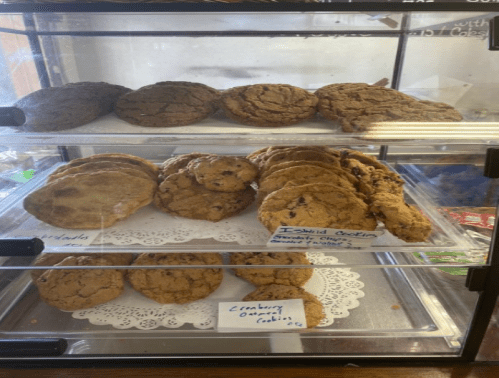 A display case with three rows of assorted cookies, including chocolate chip and oatmeal varieties.