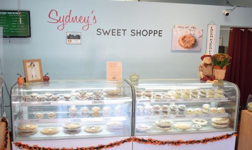 Display case filled with various baked goods at Sydney's Sweet Shoppe, with a cozy autumn-themed decor.