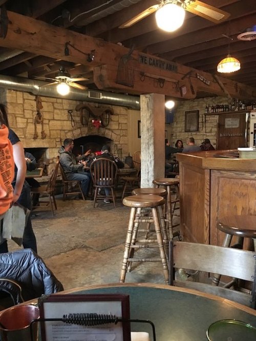 Cozy restaurant interior with wooden furniture, a fireplace, and patrons enjoying their meals in a rustic setting.