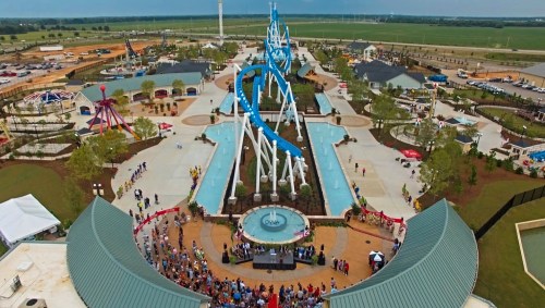 Aerial view of a water park featuring slides, pools, and attractions, with a crowd gathered in the foreground.