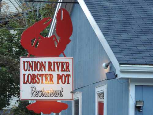 Sign for "Union River Lobster Pot Restaurant" featuring a red lobster graphic, set against a blue building.