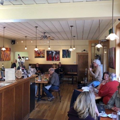 A cozy restaurant interior with diners at tables, colorful artwork on the walls, and a warm, inviting atmosphere.