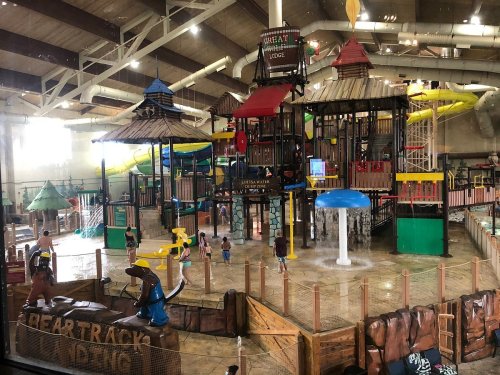 Indoor water park featuring colorful slides, play structures, and children enjoying water activities.