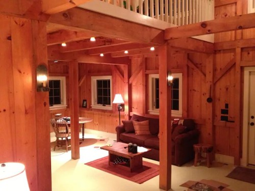 Cozy wooden interior of a cabin with a living area, dining table, and warm lighting.