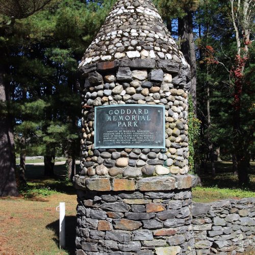 Stone tower entrance of Goddard Memorial Park, featuring a plaque and surrounded by trees and greenery.